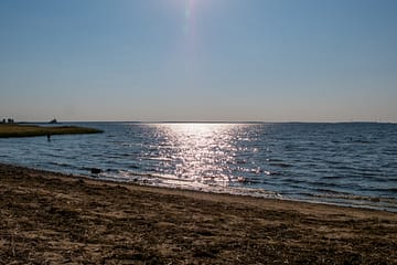 kuva merenrannasta jossa vedessä kimaltelee auringon heijastus